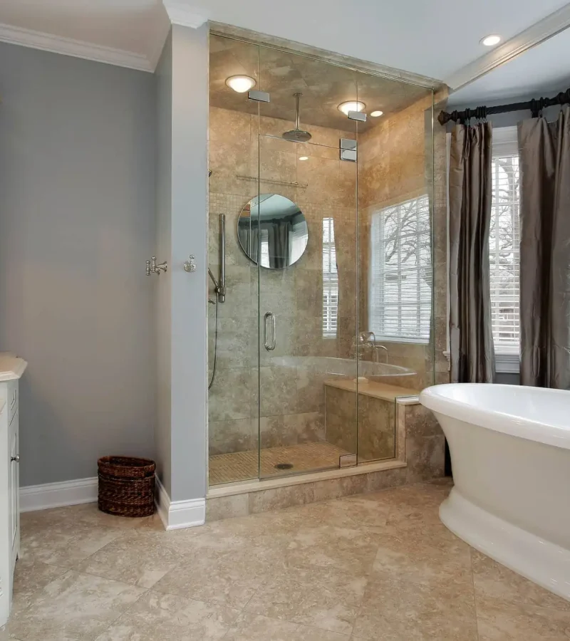 Luxury bathroom with a large bathtub, double vanity, and warm ambient lighting. Traditional style, with marble floor and 3 walls of shower.