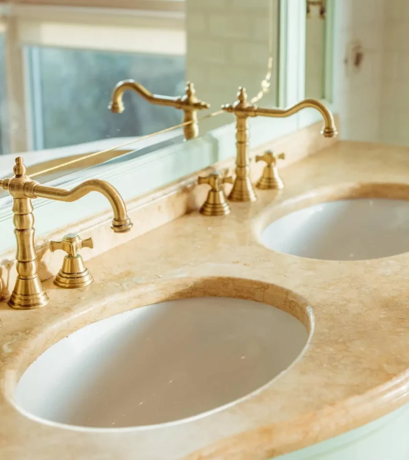 "Modern" antique faucets in gold finish, under counter sinks with marble top.