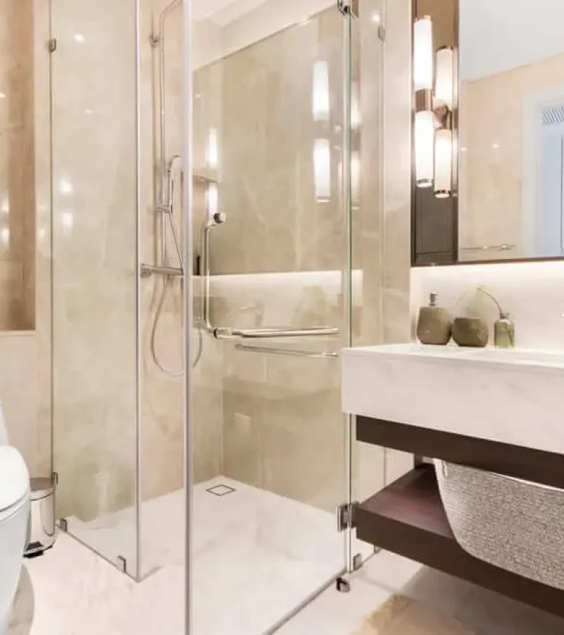Minimalist style in earth tones with corner glass walk0in shower, one piece toilet and suspended counter with one piece sink. Unique sidelights add nice accent.